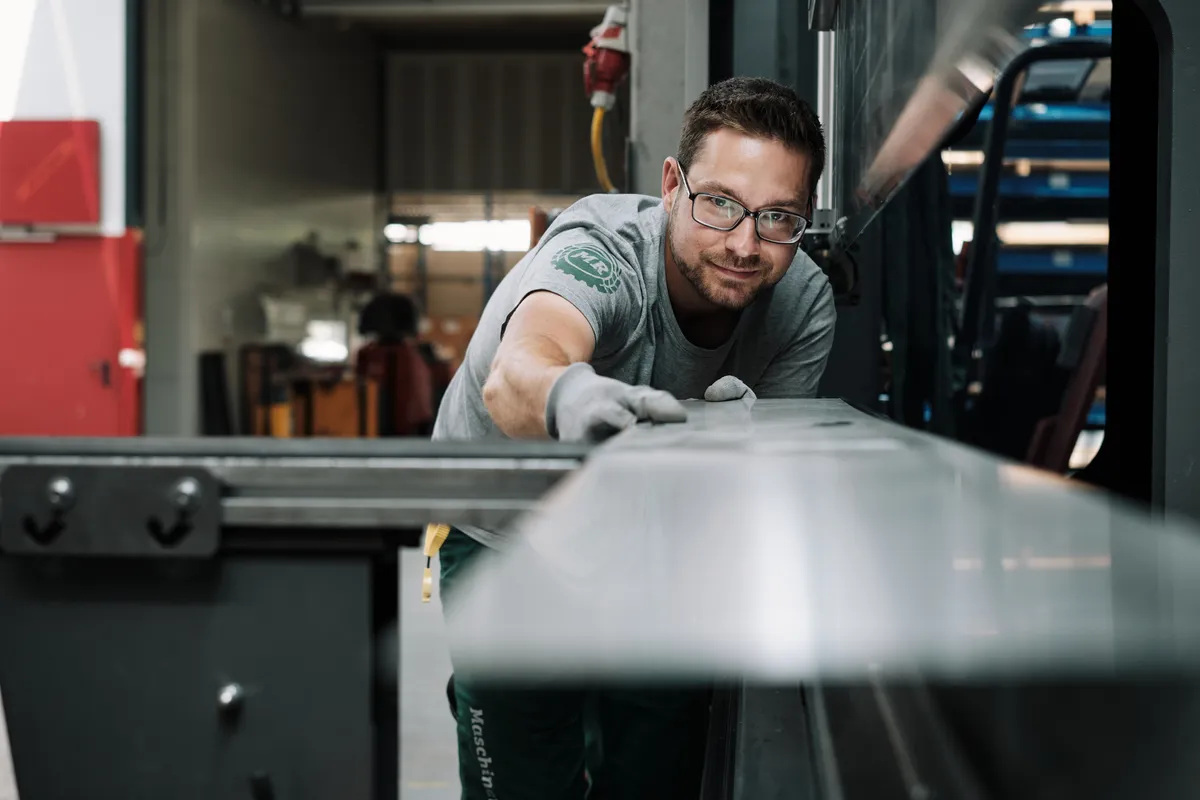 Mitarbeiter in der Werkstatt des Maschinenrings prüft ein Blech an der Maschine