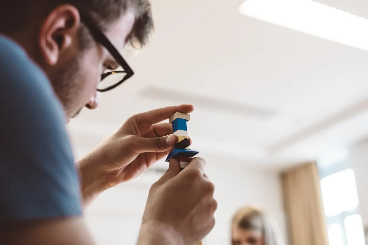 Ein Teilnehmer mit Brille betrachtet eine kleine Lego-Figur in seinen Händen.