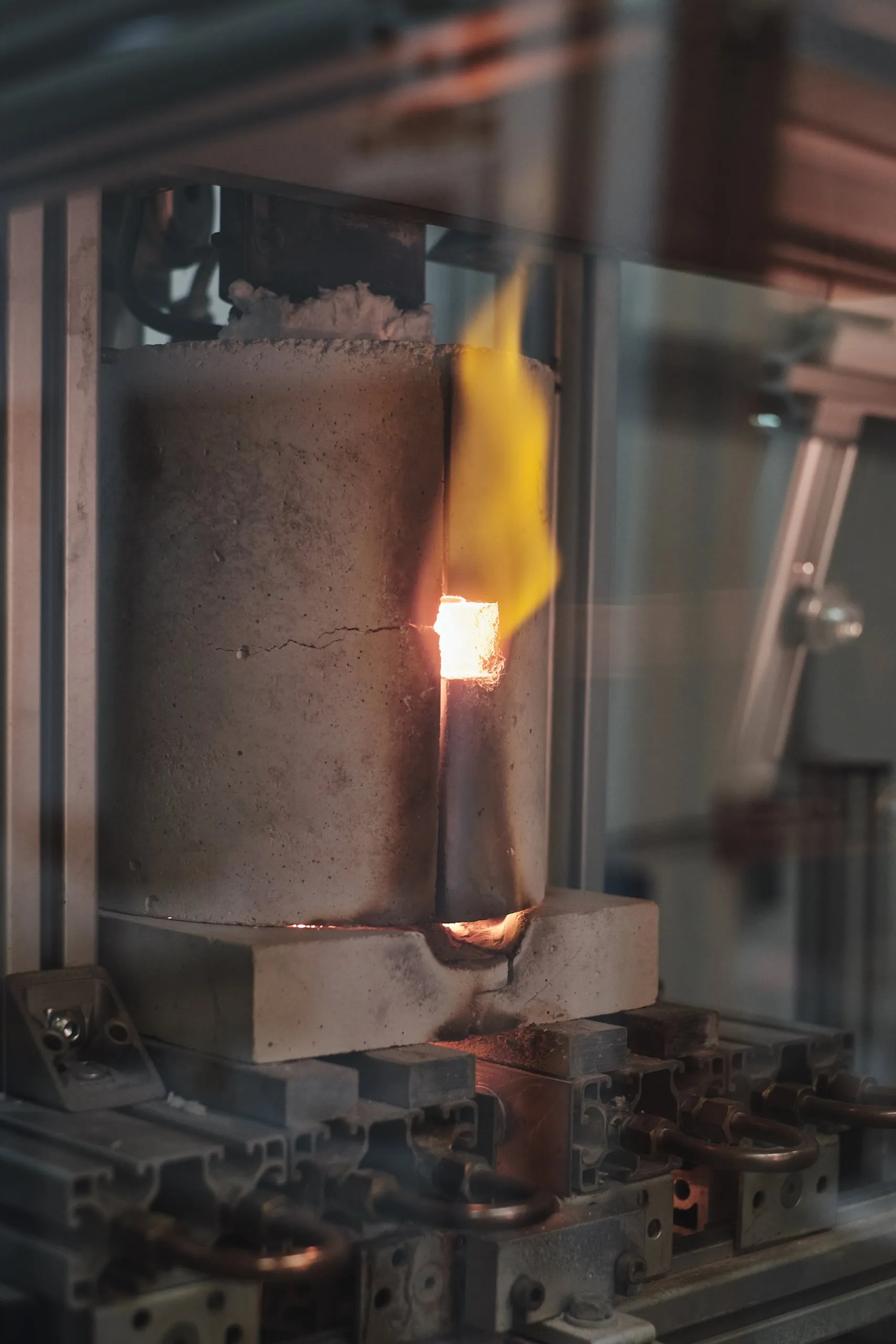 Hinter Glas brennt eine kleine Flamme in einer Brennanlage.