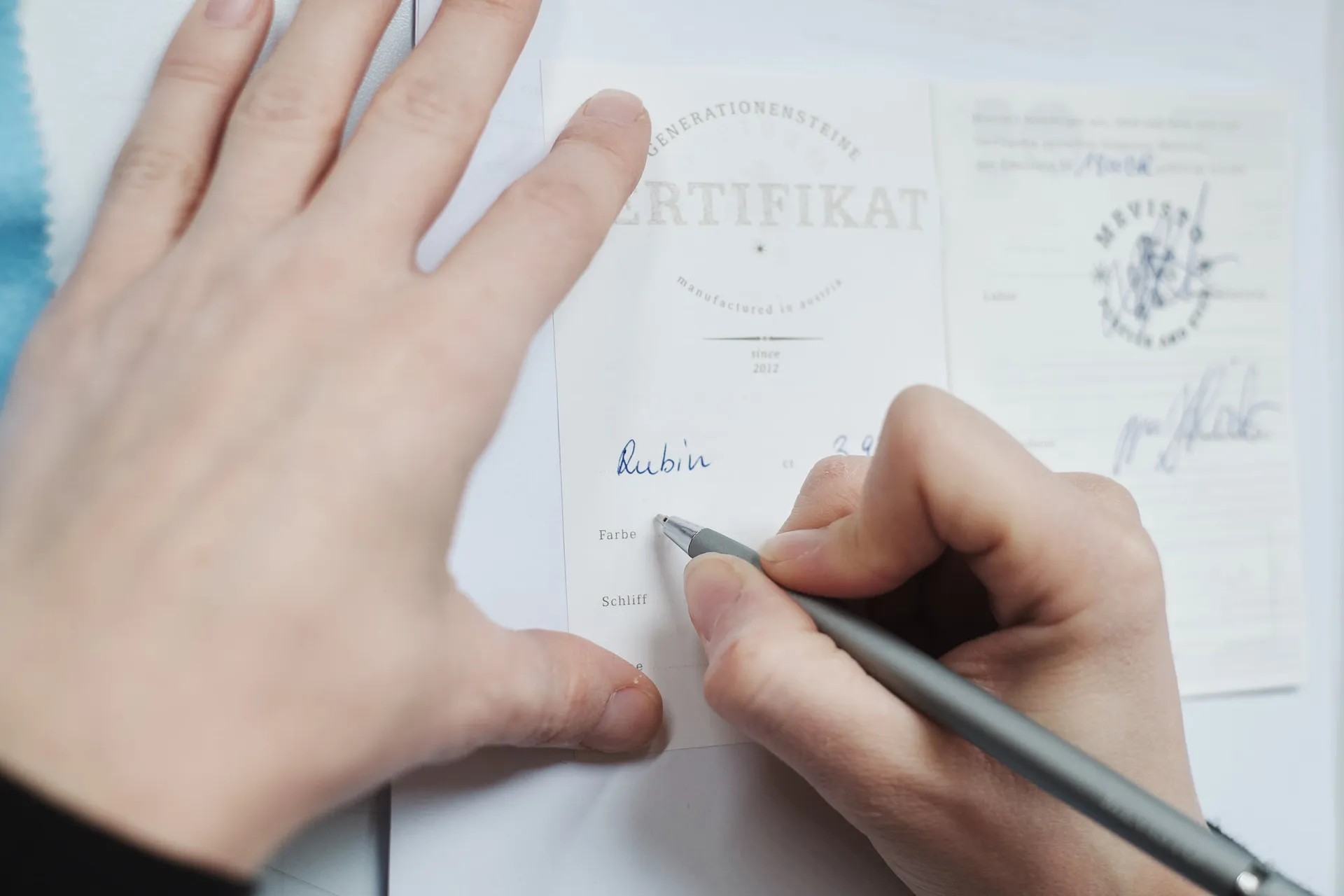 Eine Hand unterschreibt ein Zertifikat für einen Rubin.